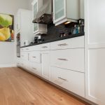 Wire-Brushed Natural Hickory Wood Flooring in Kitchen with Black Glass Back Splash